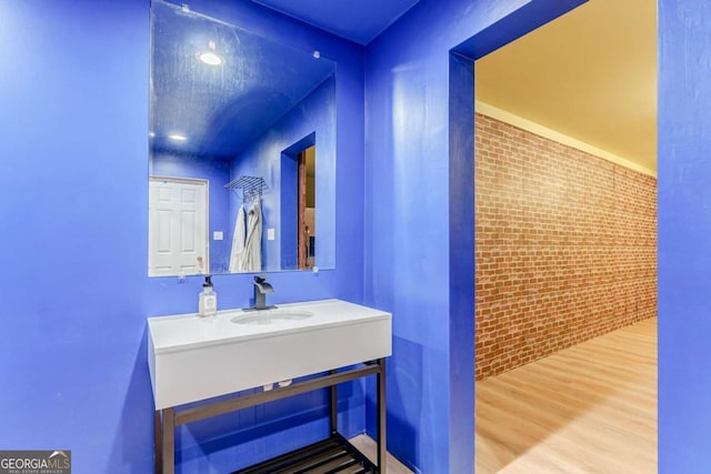 bathroom featuring brick wall, wood finished floors, and vanity