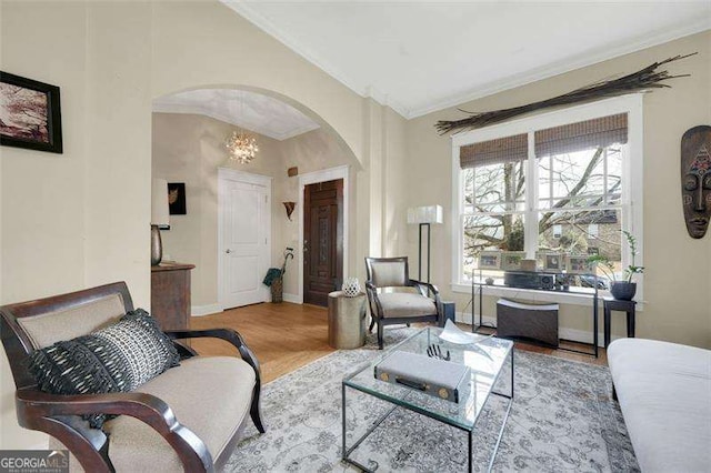 sitting room featuring ornamental molding, wood-type flooring, and a notable chandelier