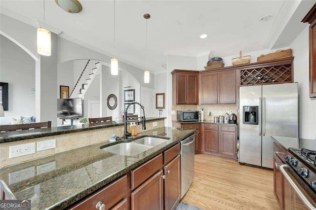 kitchen featuring dark stone countertops, sink, decorative light fixtures, and appliances with stainless steel finishes