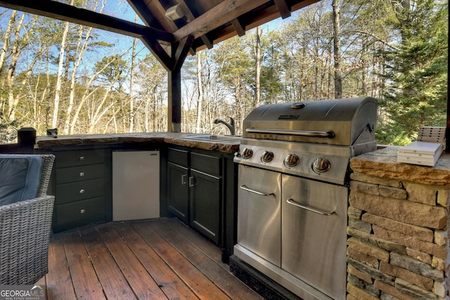 view of patio with exterior kitchen, a wooden deck, area for grilling, and sink