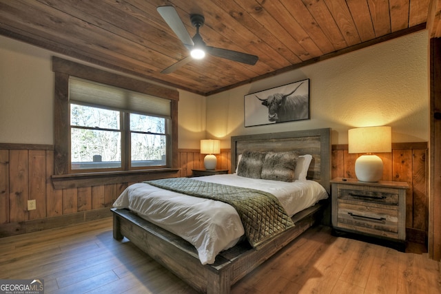 bedroom with wood ceiling, wood walls, ceiling fan, and hardwood / wood-style flooring