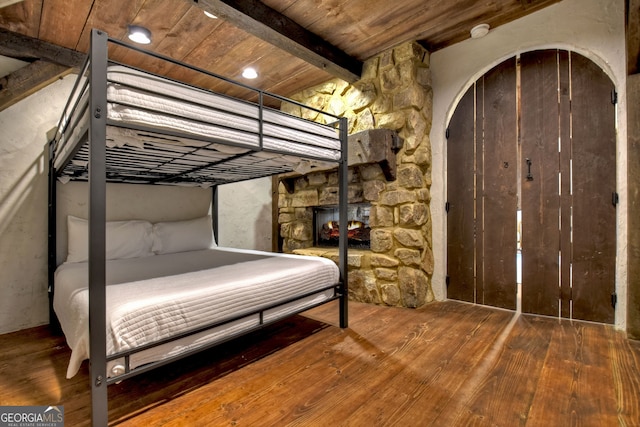 unfurnished bedroom with beam ceiling, hardwood / wood-style floors, and wooden ceiling