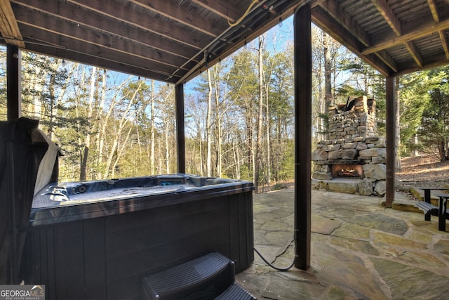 view of patio featuring a hot tub and an outdoor stone fireplace