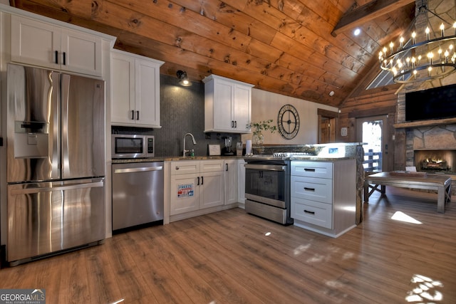 kitchen with wood ceiling, appliances with stainless steel finishes, light stone countertops, and white cabinets