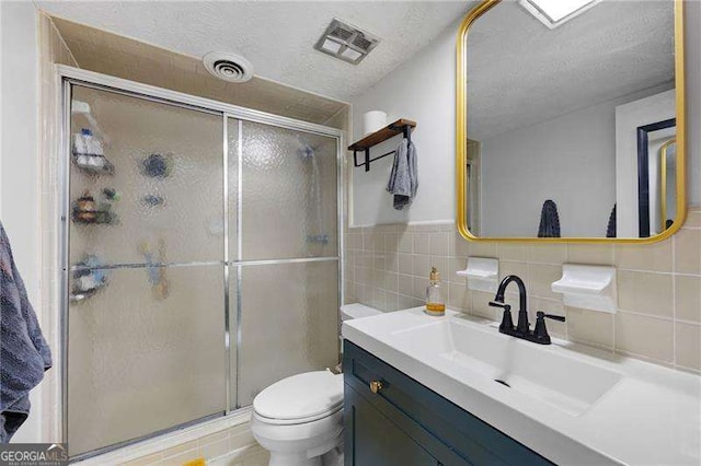 bathroom featuring tile walls, an enclosed shower, a textured ceiling, and toilet