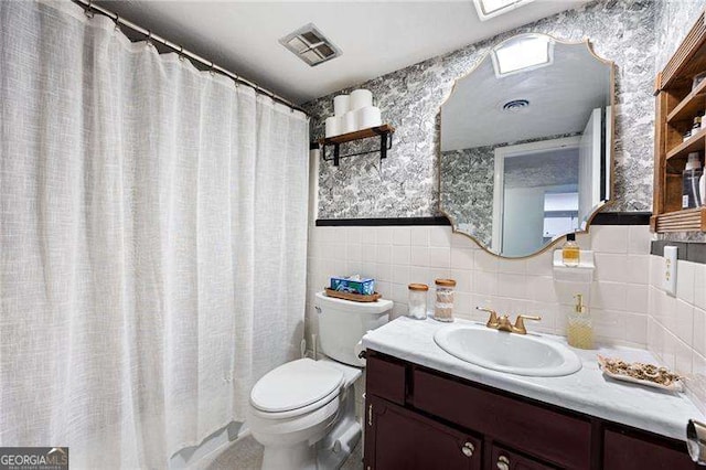 bathroom with vanity, tile walls, and toilet