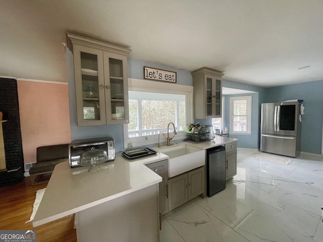 kitchen featuring dishwashing machine, sink, gray cabinetry, and stainless steel refrigerator