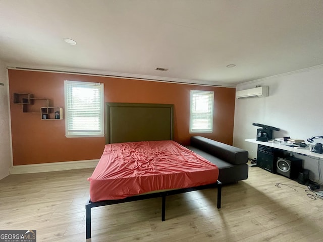 bedroom with a wall mounted AC, multiple windows, and light wood-type flooring