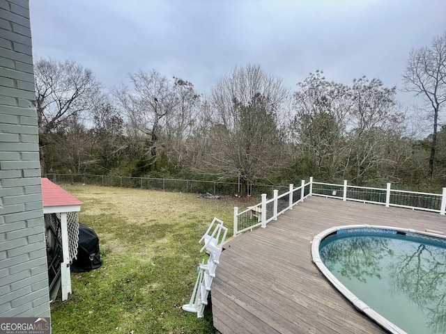 view of swimming pool with a wooden deck and a lawn