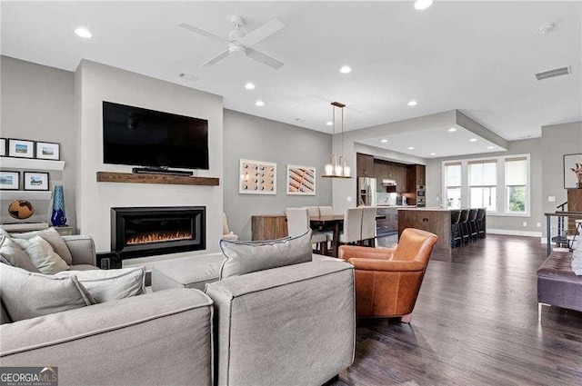 living room featuring ceiling fan and dark hardwood / wood-style floors