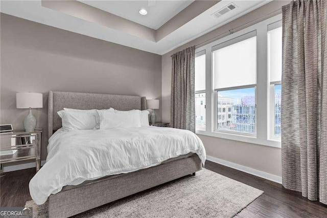 bedroom featuring dark hardwood / wood-style flooring and a raised ceiling