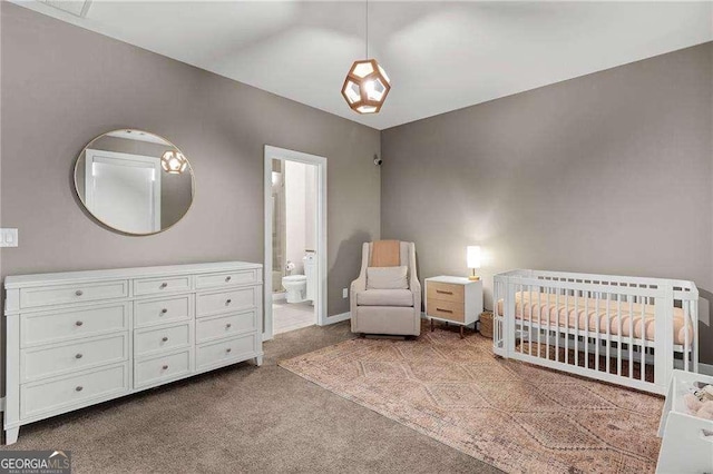 carpeted bedroom featuring a nursery area and ensuite bathroom