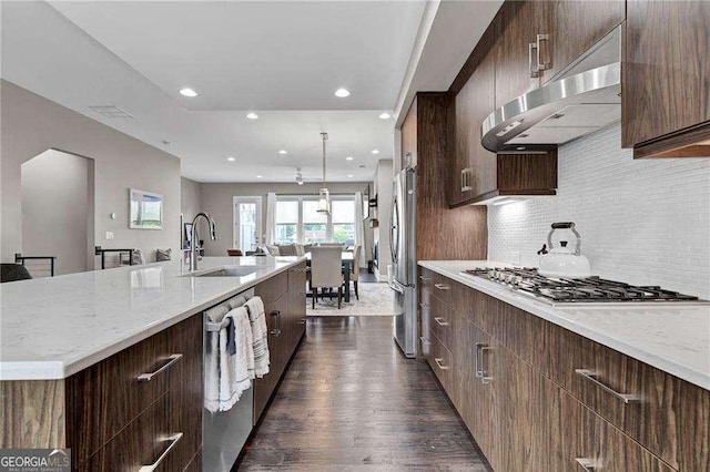 kitchen featuring extractor fan, sink, backsplash, a kitchen island with sink, and stainless steel appliances