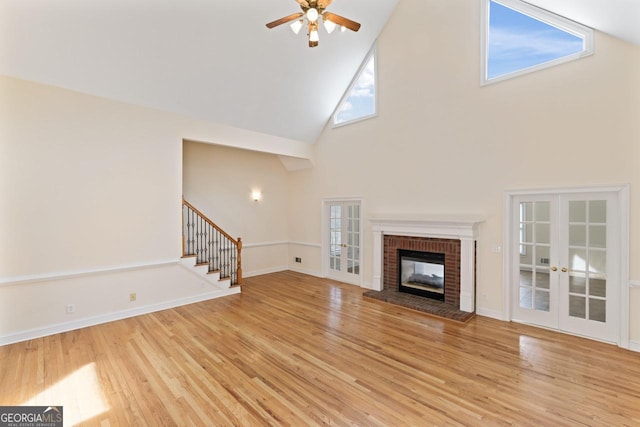 unfurnished living room with ceiling fan, a fireplace, light hardwood / wood-style floors, and french doors