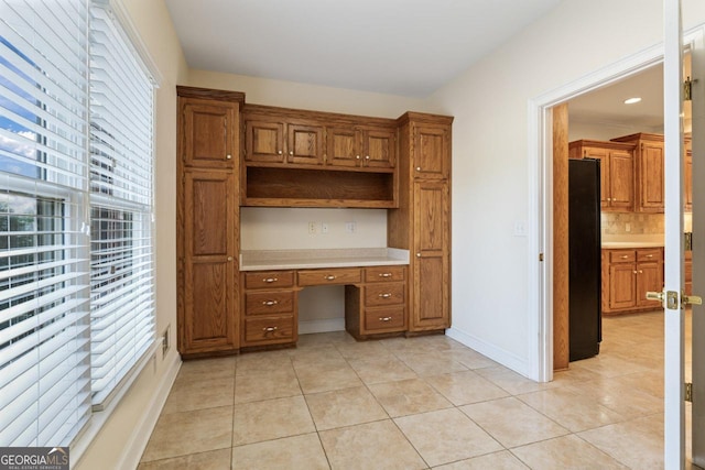 unfurnished office featuring light tile patterned flooring and built in desk