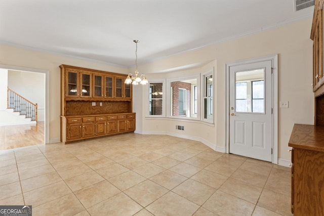 unfurnished dining area with crown molding, light tile patterned flooring, and a notable chandelier