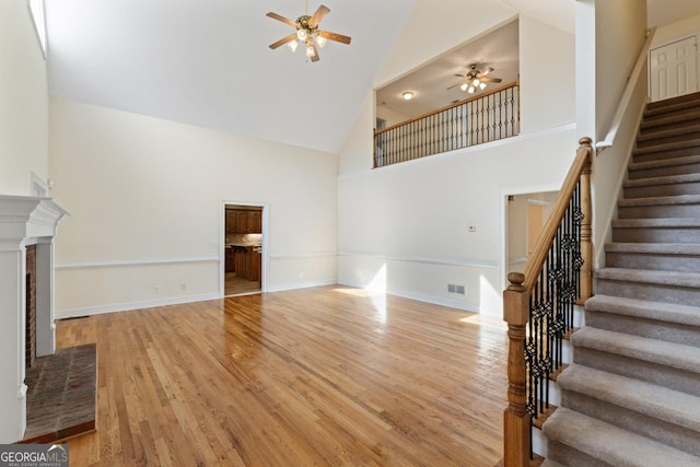 unfurnished living room with high vaulted ceiling, ceiling fan, and light hardwood / wood-style flooring