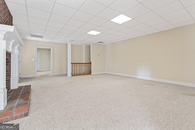 basement with carpet, a drop ceiling, and a brick fireplace