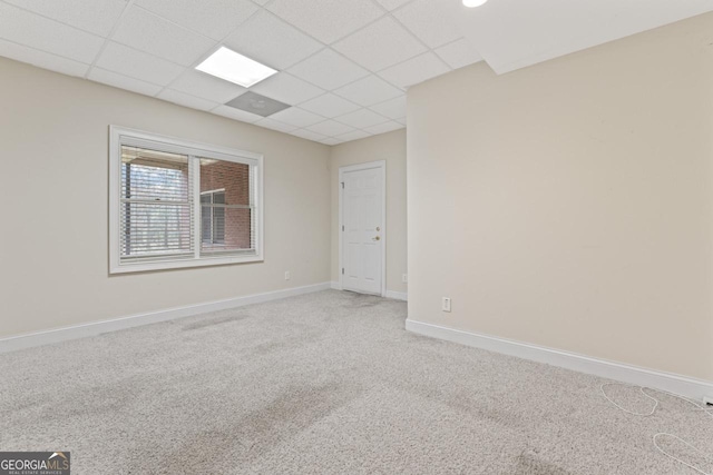 spare room featuring a paneled ceiling and carpet flooring