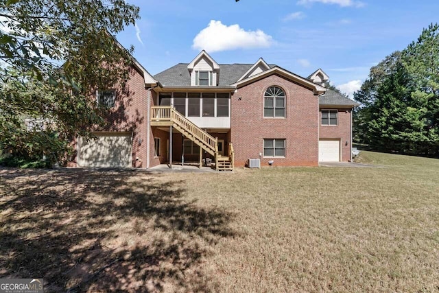 back of house featuring a garage, a sunroom, and a lawn