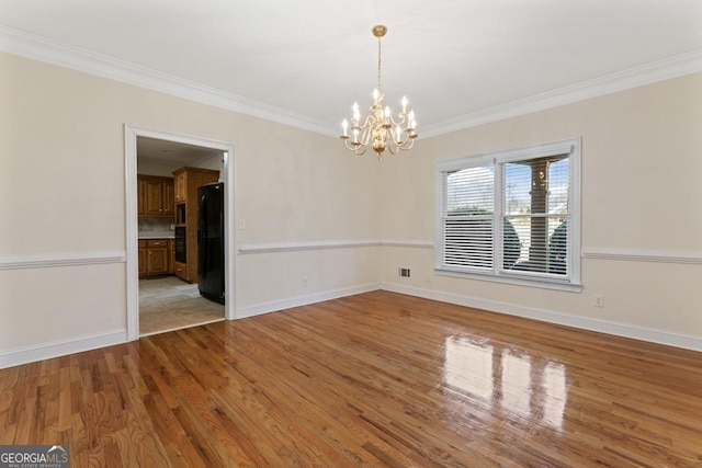 empty room featuring a notable chandelier, crown molding, and light wood-type flooring