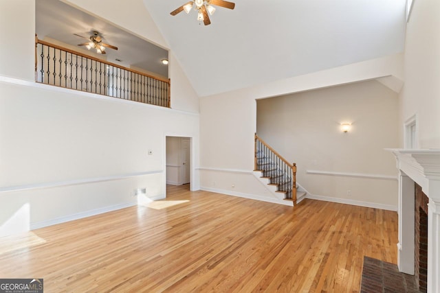 unfurnished living room featuring ceiling fan, high vaulted ceiling, and light wood-type flooring