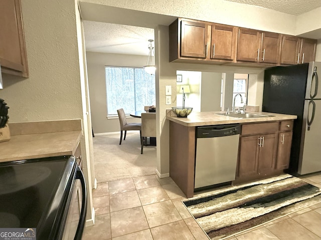 kitchen featuring sink, hanging light fixtures, stainless steel appliances, a textured ceiling, and light tile patterned flooring