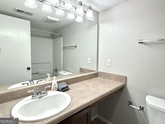 bathroom featuring vanity, toilet, and a textured ceiling