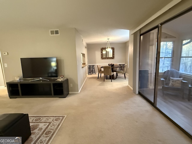 carpeted living room with a notable chandelier