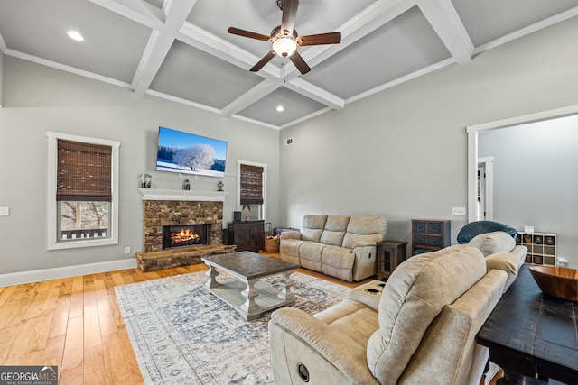 living room with hardwood / wood-style flooring, ceiling fan, coffered ceiling, a stone fireplace, and beamed ceiling