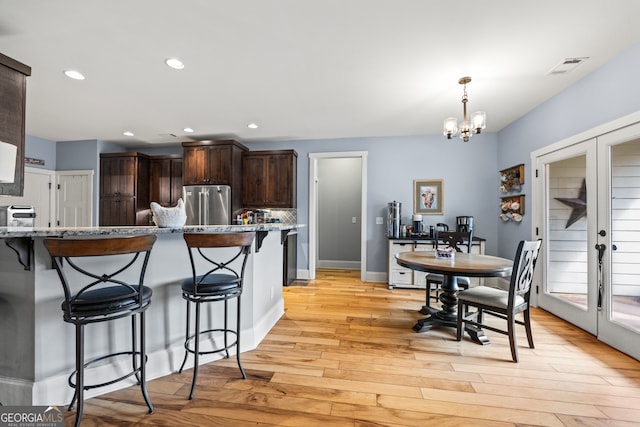 kitchen featuring high quality fridge, a breakfast bar area, dark brown cabinetry, and french doors