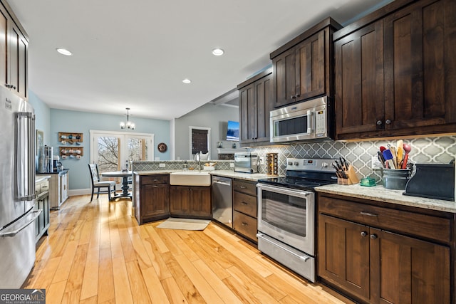 kitchen featuring backsplash, decorative light fixtures, dark brown cabinets, and appliances with stainless steel finishes