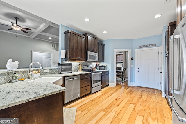 kitchen featuring sink, appliances with stainless steel finishes, backsplash, coffered ceiling, and light stone countertops