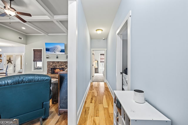 hall with beamed ceiling, coffered ceiling, and light hardwood / wood-style floors