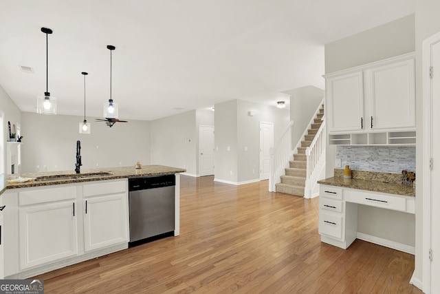 kitchen with stone countertops, sink, stainless steel dishwasher, and white cabinets