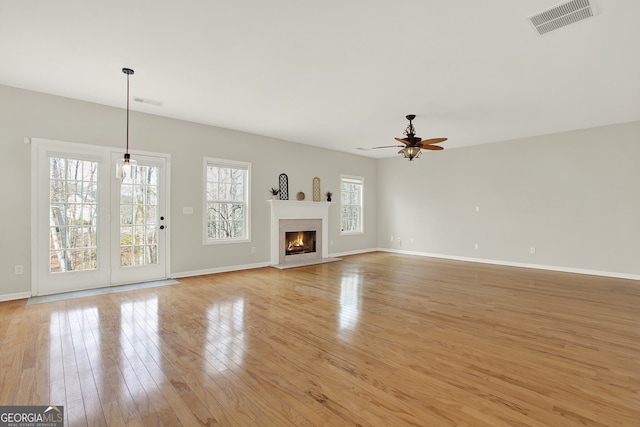 unfurnished living room with ceiling fan, a fireplace, and light hardwood / wood-style flooring