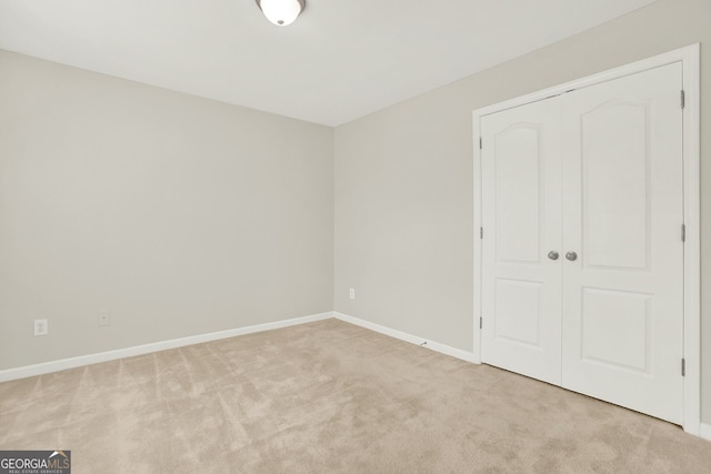 unfurnished bedroom with light carpet and a closet