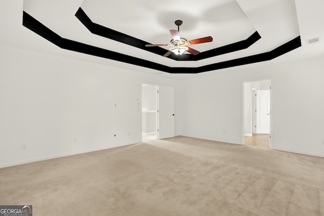 carpeted spare room featuring ceiling fan and a raised ceiling