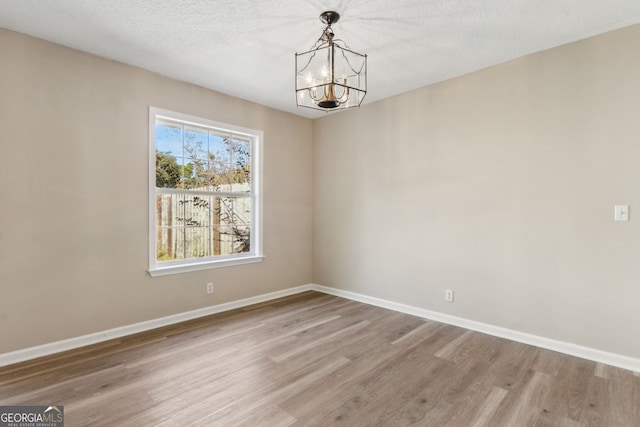 unfurnished dining area featuring an inviting chandelier, wood-type flooring, and a textured ceiling