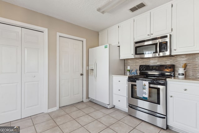 kitchen with light tile patterned flooring, white cabinetry, a textured ceiling, appliances with stainless steel finishes, and backsplash