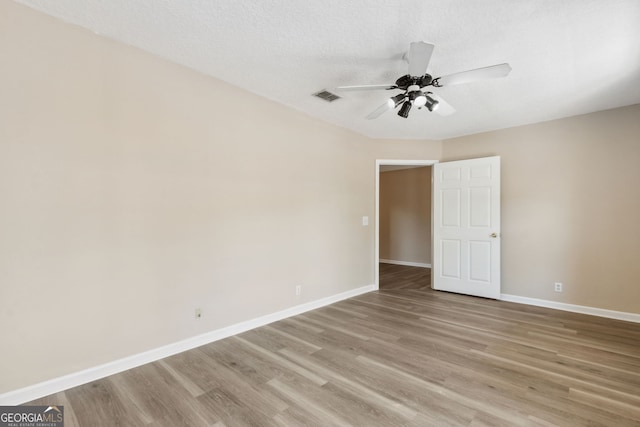 empty room with ceiling fan, light hardwood / wood-style floors, and a textured ceiling