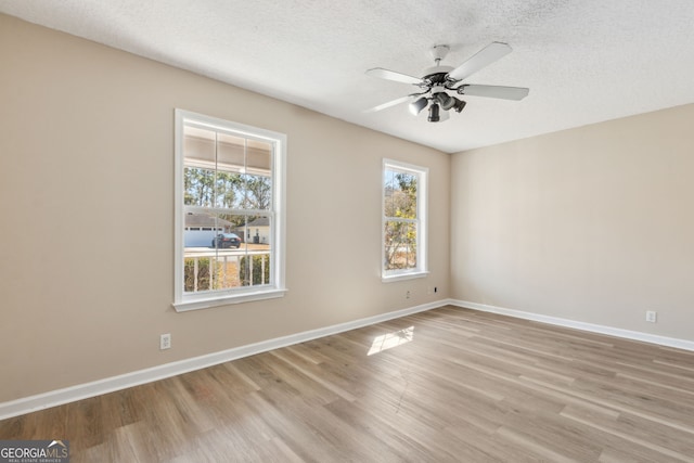 empty room with ceiling fan, light hardwood / wood-style floors, and a textured ceiling