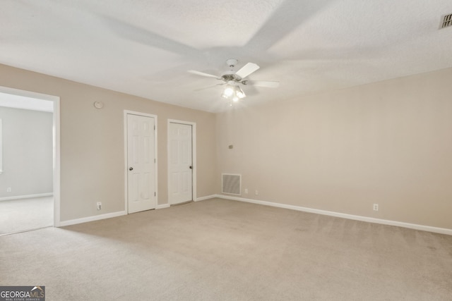 unfurnished bedroom featuring ceiling fan, light colored carpet, and a textured ceiling