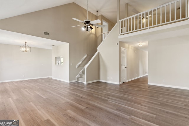 unfurnished living room featuring vaulted ceiling, ceiling fan with notable chandelier, and hardwood / wood-style floors