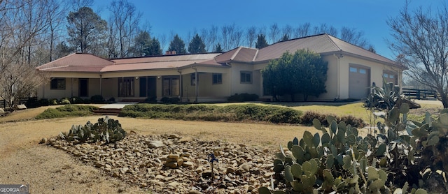 view of front of house featuring a garage, fence, and stucco siding