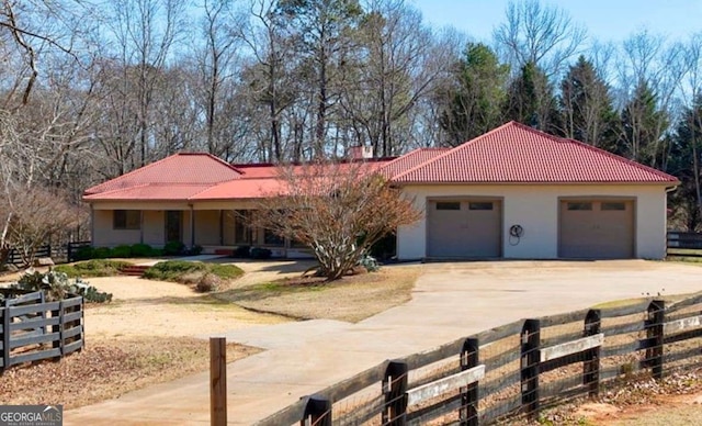 view of front of home featuring an attached garage, fence, concrete driveway, a tiled roof, and stucco siding