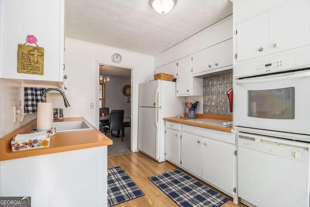 kitchen featuring sink, white cabinetry, light hardwood / wood-style flooring, a textured ceiling, and white appliances