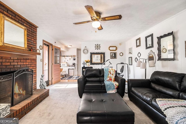 living room with ceiling fan, a brick fireplace, light colored carpet, and a textured ceiling