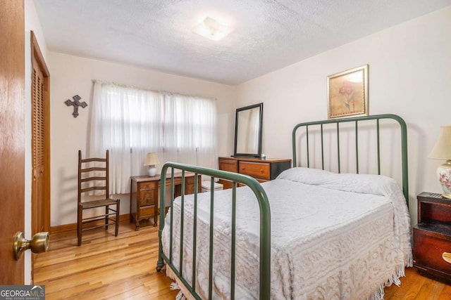 bedroom with a closet, wood-type flooring, and a textured ceiling