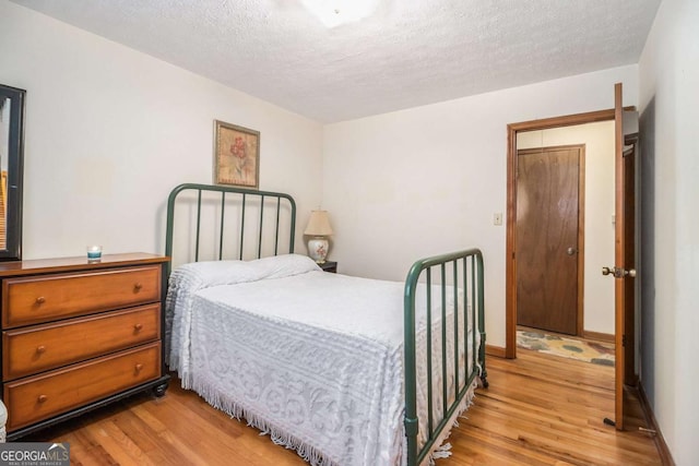 bedroom with light hardwood / wood-style floors and a textured ceiling